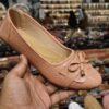 Peach colored ballet flat with bow detail held in hand, displayed in a jain chappal store located in delhi shahdara.