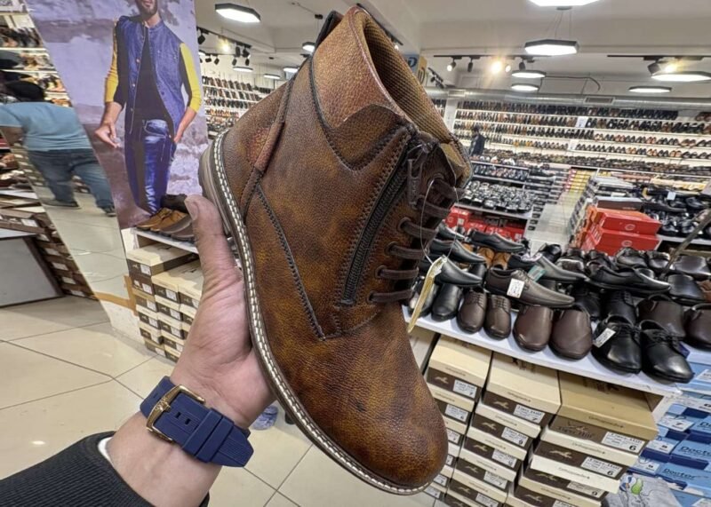 Tiger Hill leather bootswith brown accents featuring lace-up and zipper designs, displayed on a tile floor at jain chappal store shahdara with branded packaging in the background.
